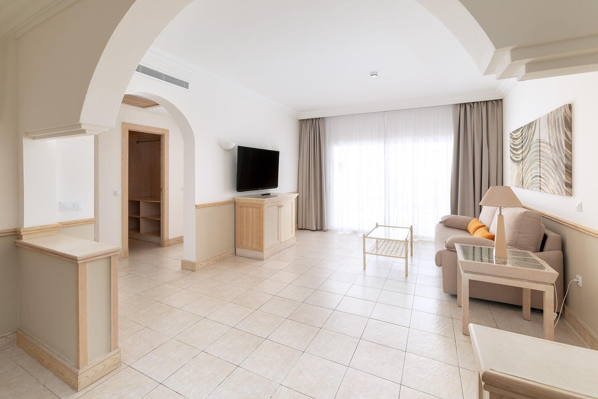 Amplia sala de estar con televisión, sofá, mesa de centro y comedor.