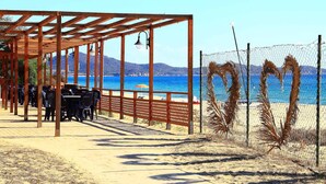 Un café frente a la playa con terraza, una pérgola de madera y vistas al mar.