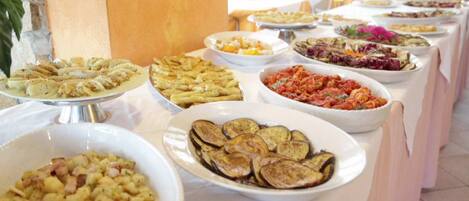 A buffet table with various dishes, including pasta, salads, and vegetables.