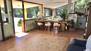 Un salón espacioso con un ventanal grande, una mesa de madera con taburetes, un sofá y una mesa baja con revistas.