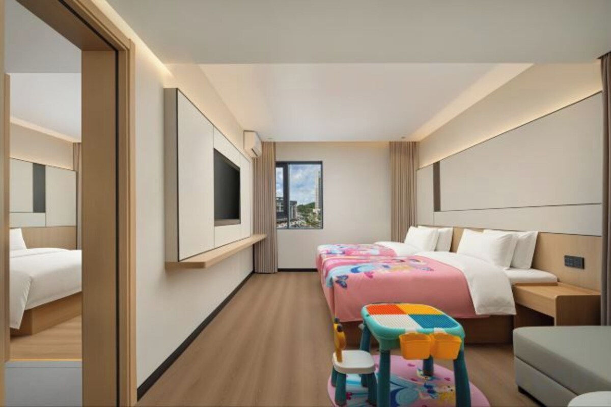 A hotel room with a bed, a desk, a chair, a TV, and a window.