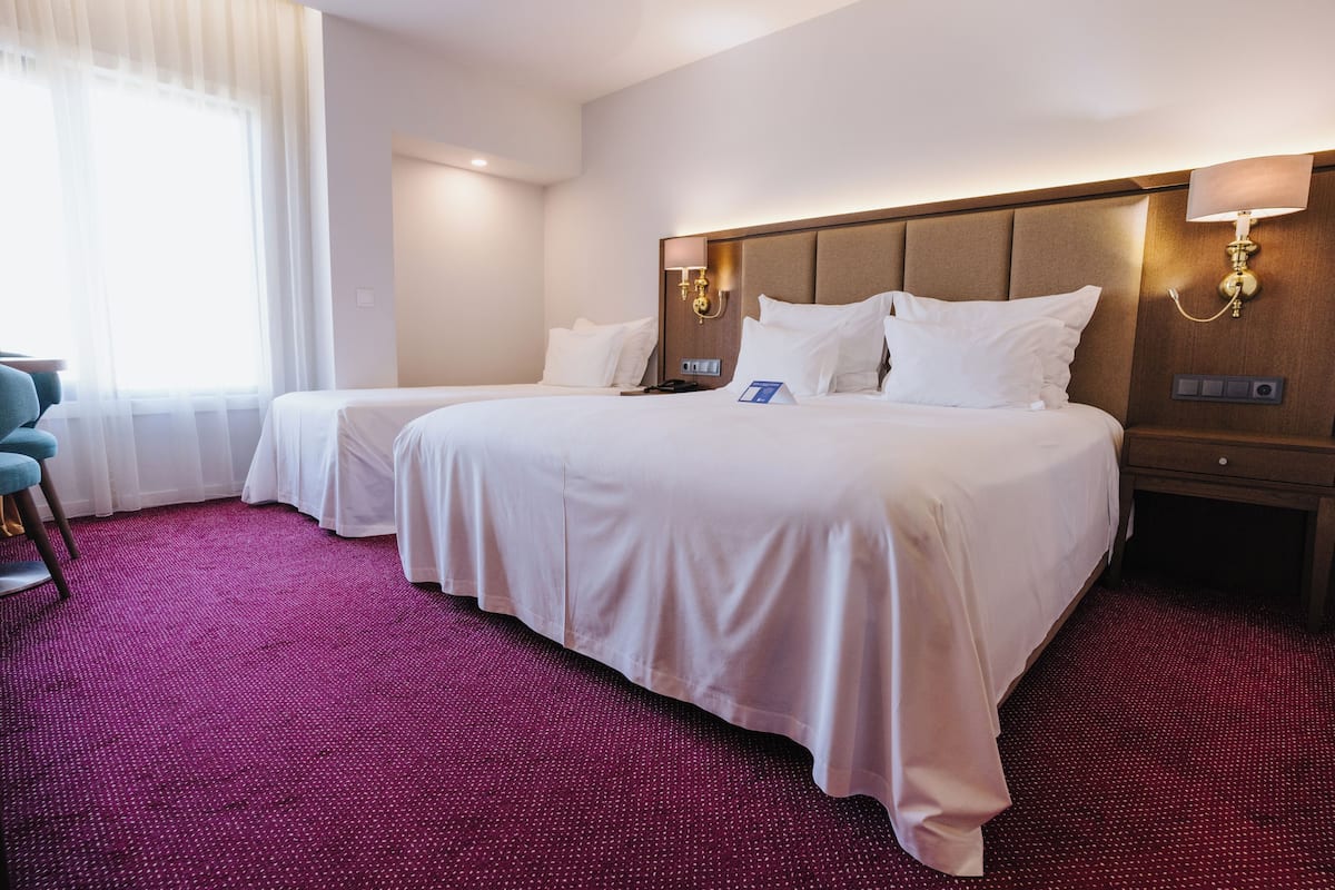A hotel room with two beds, a desk, and a chair.
