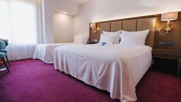 A hotel room with two beds, a desk, and a chair.