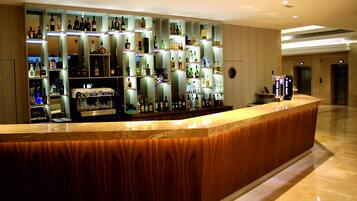 A bar area with a marble countertop and shelves stocked with various liquor bottles.