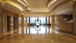 A spacious lobby with a polished marble floor, a reception desk, and a large glass sculpture in the center.