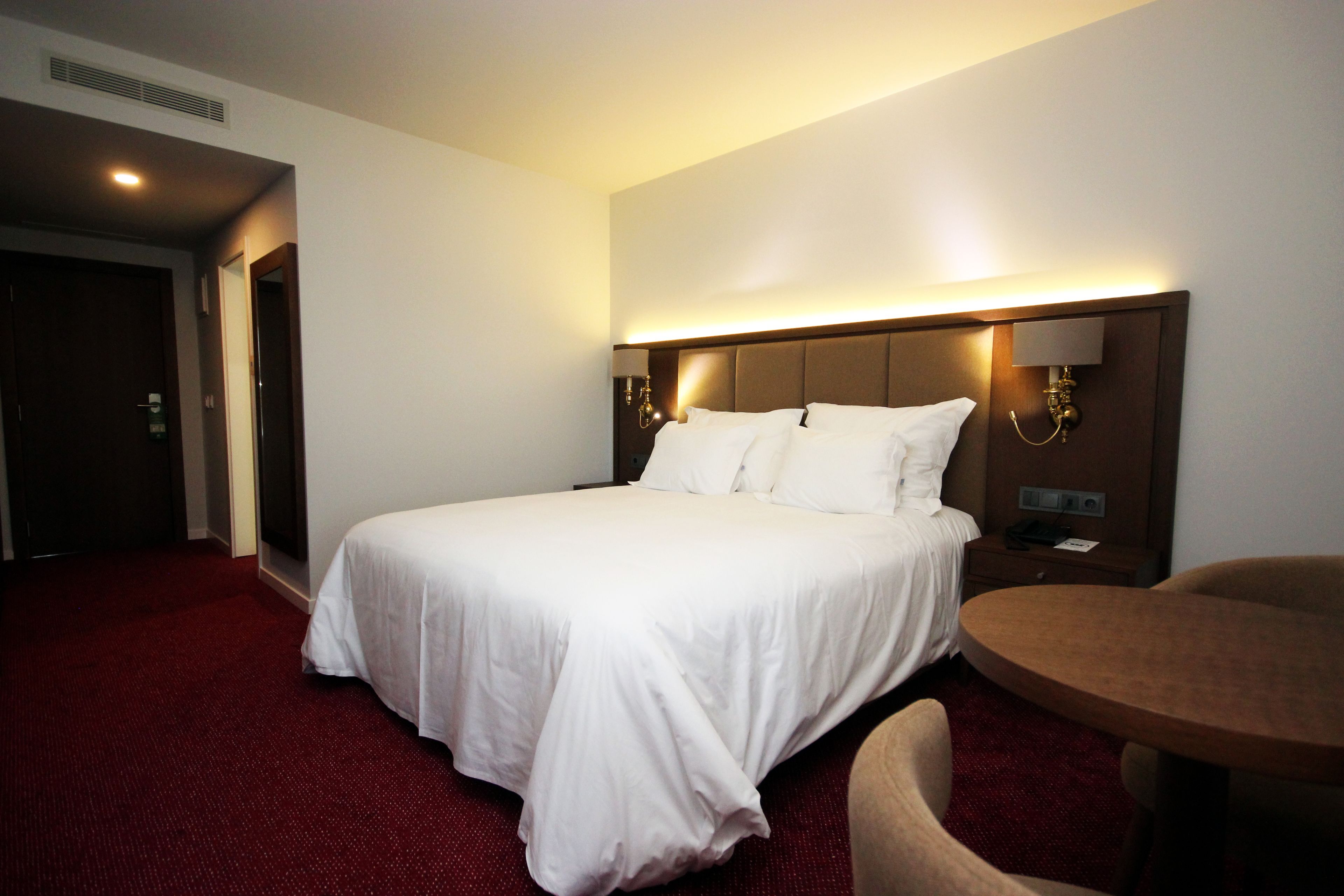Una habitación de hotel con una cama grande, una mesa redonda y una silla.