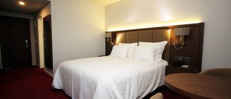 A hotel room with a large bed, a round table, and a chair.