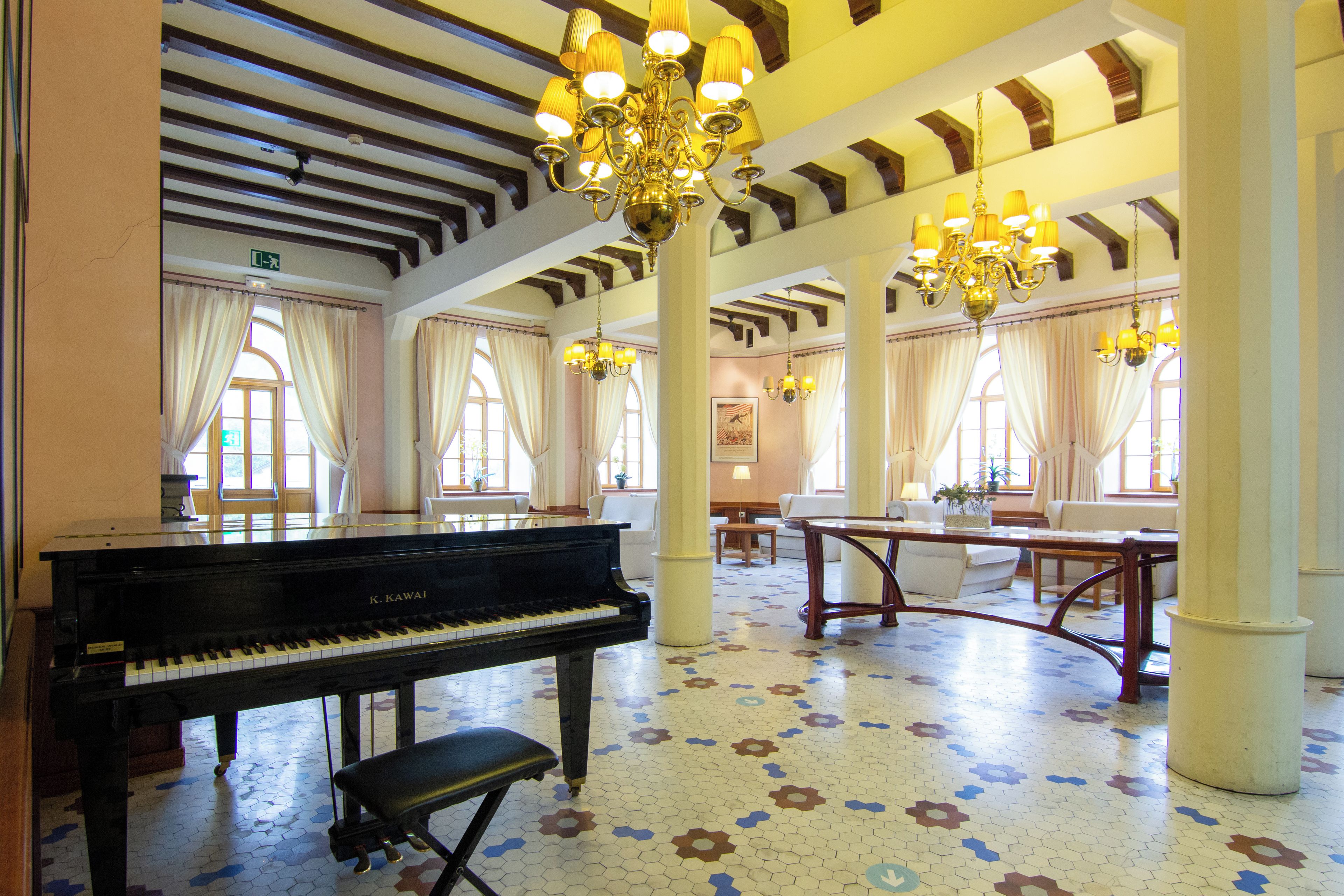 Un vestíbulo espacioso con un piano de cola, techos altos y candelabros ornamentales.
