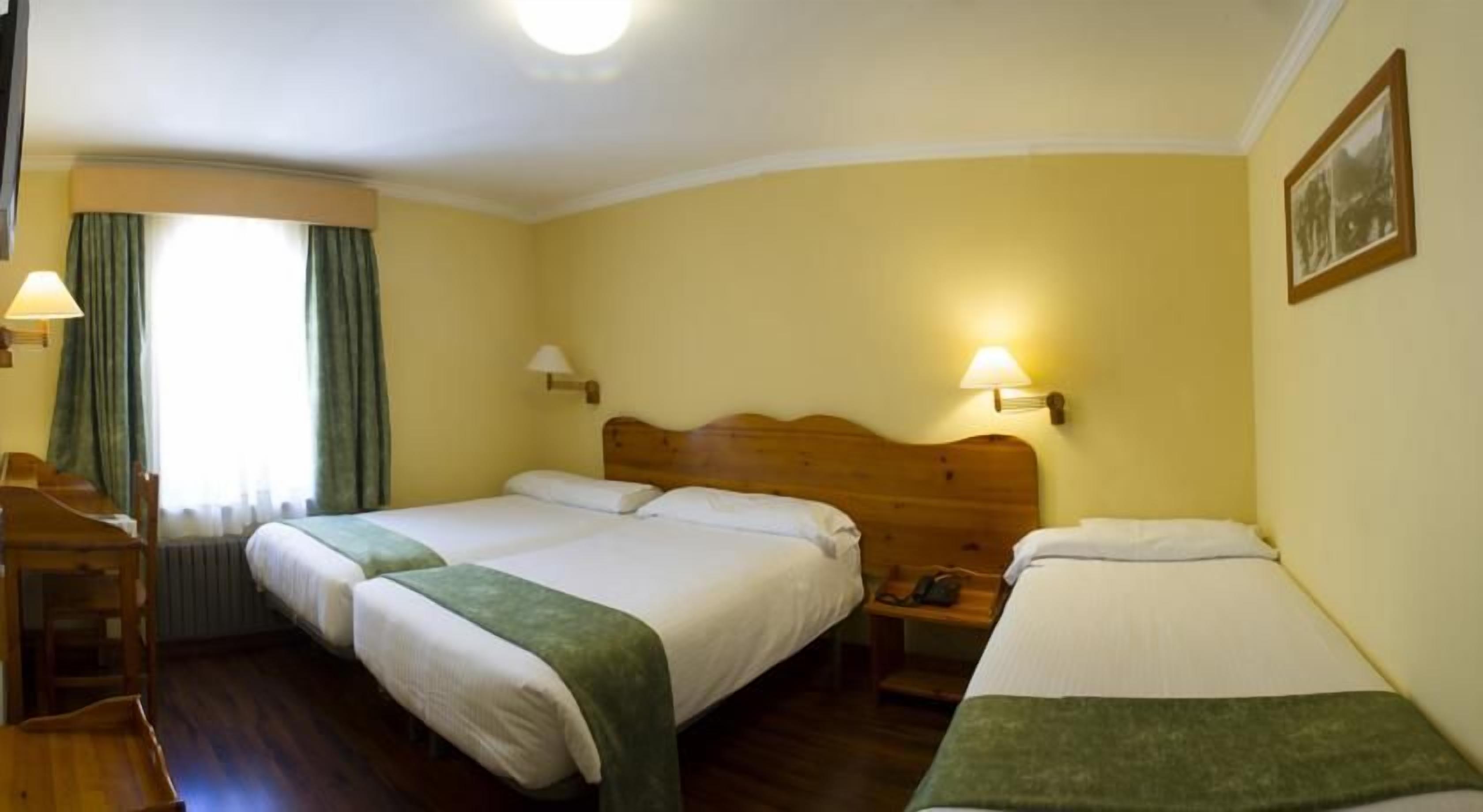 A hotel room with two beds, a desk, and a chair.