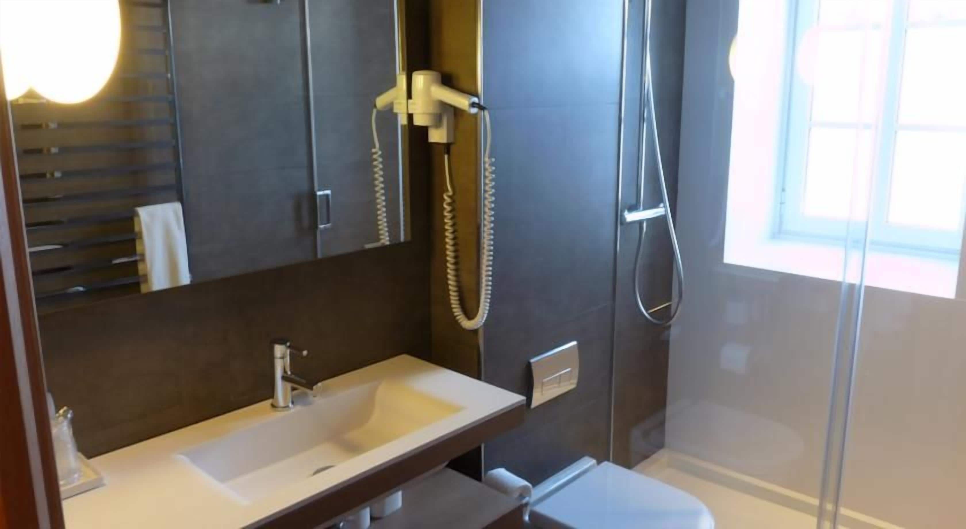 Un bany modern amb un lavabo integrat, una dutxa de mà i una cabina de dutxa amb portes de vidre.