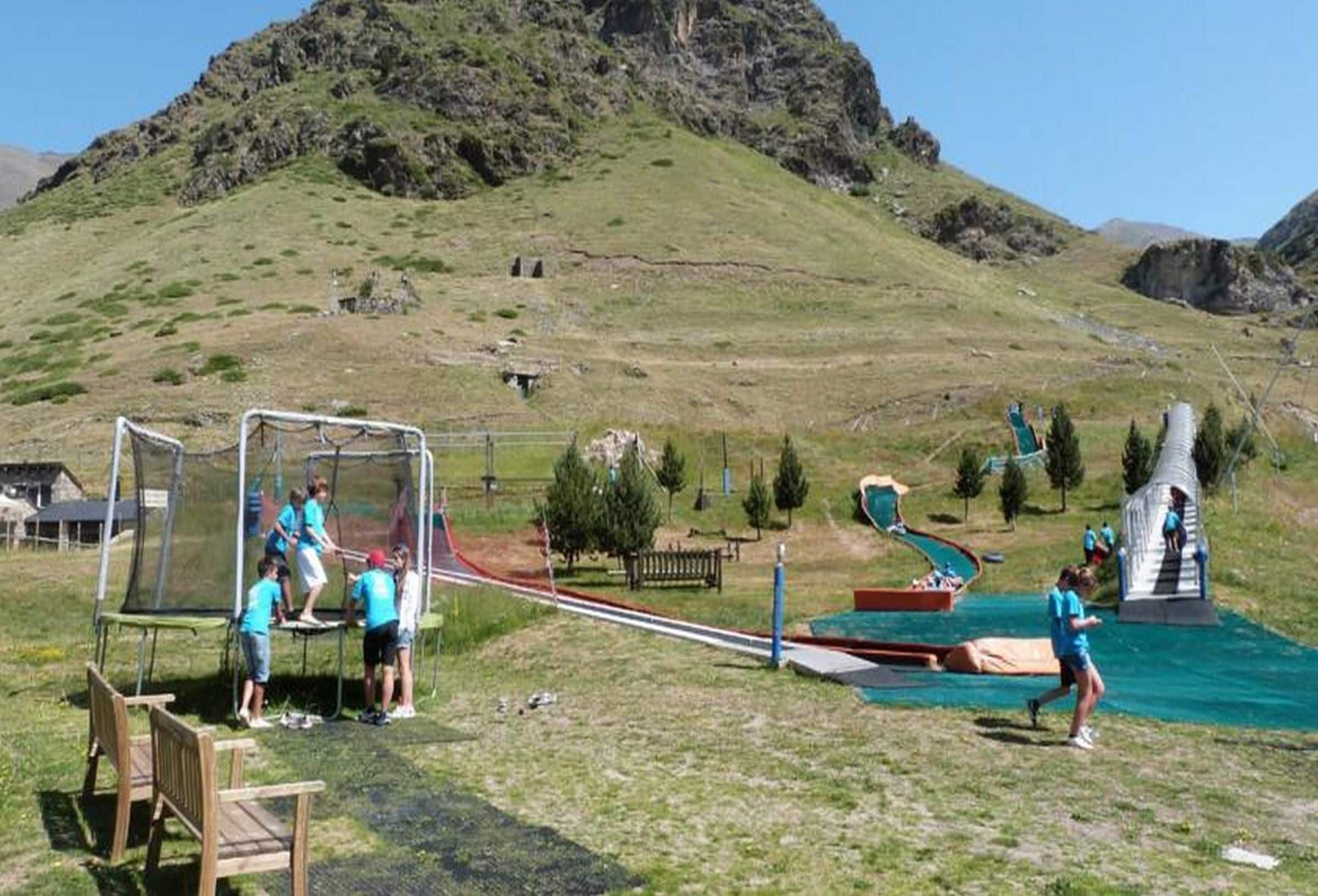 Un parque infantil con un arco de fútbol, toboganes y una pequeña piscina.