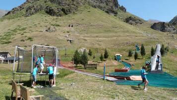 Un parque infantil con un arco de fútbol, toboganes y una pequeña piscina.