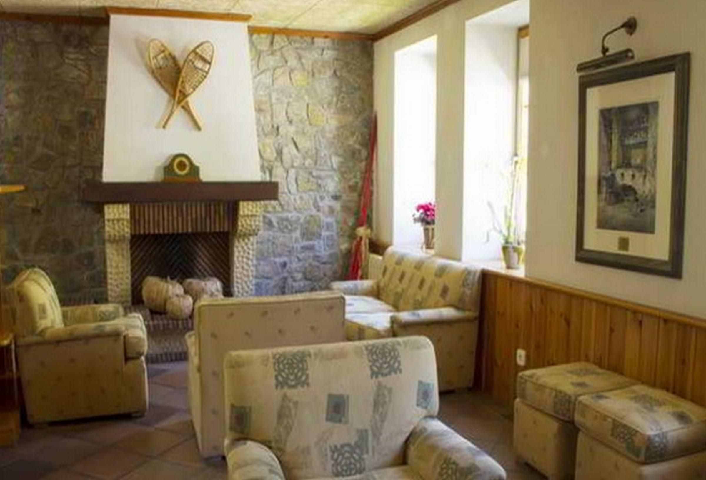 Una sala de estar acogedora con chimenea de piedra, muebles con estampado y un cuadro en la pared.