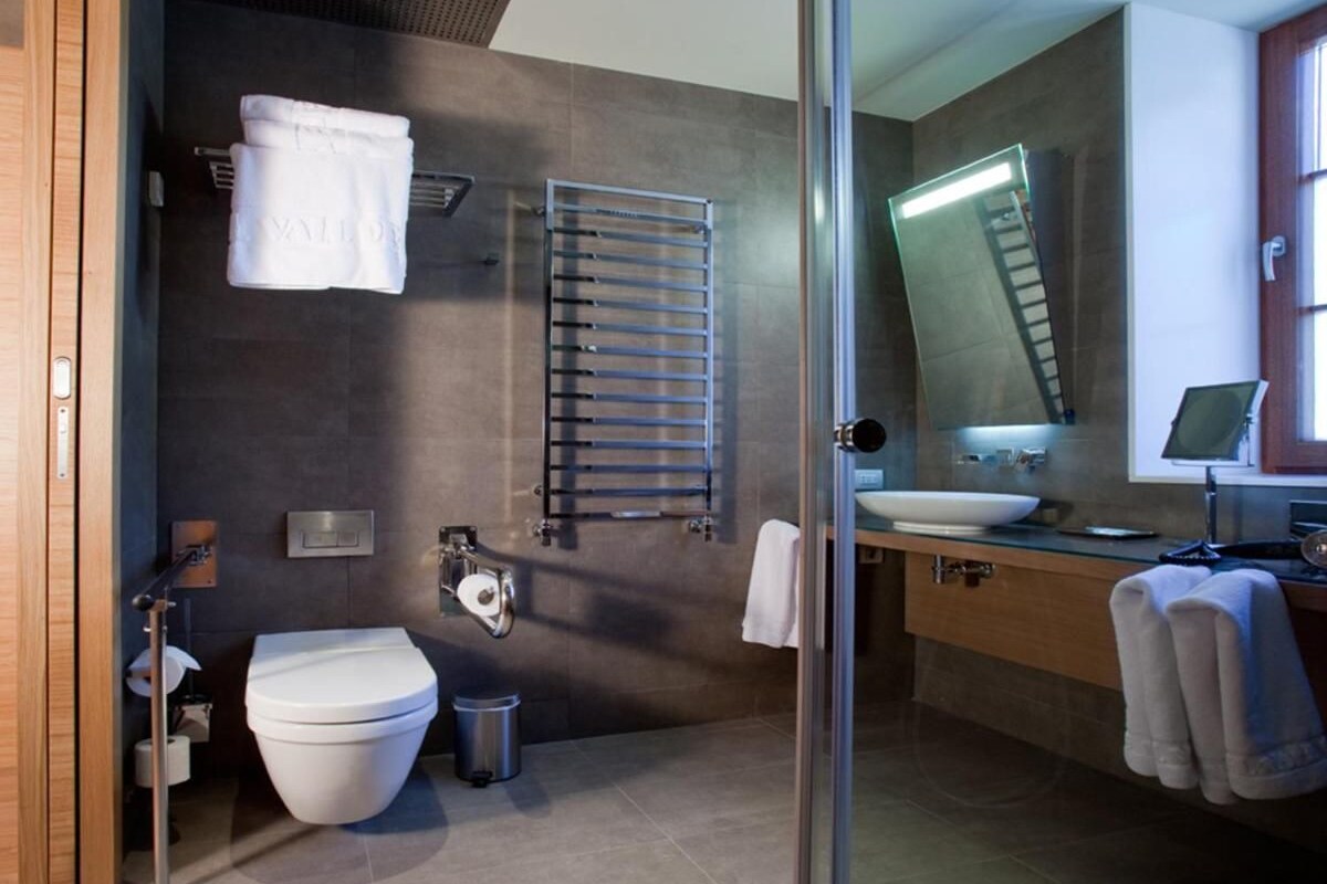 A modern bathroom with a toilet, sink, and glass shower enclosure.