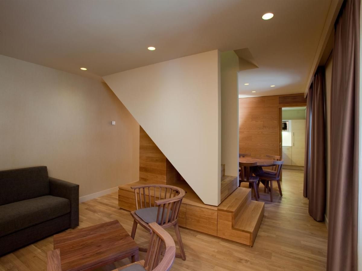 Una sala de estar moderna con una escalera de madera, un comedor y un sofá.