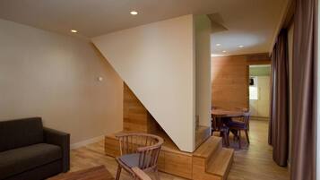 Una sala de estar moderna con una escalera de madera, un comedor y un sofá.