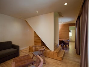 A modern living room with a wooden staircase, a dining area, and a sofa. - Vall de Nuria (Queralbs)