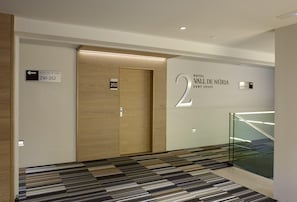 Interior de hotel con diseño moderno, que incluye una puerta de madera, un cartel con número y una escalera con alfombra estampada.