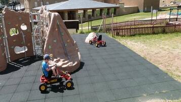 Children can play and explore in a secure, fenced area with a climbing structure and seating.