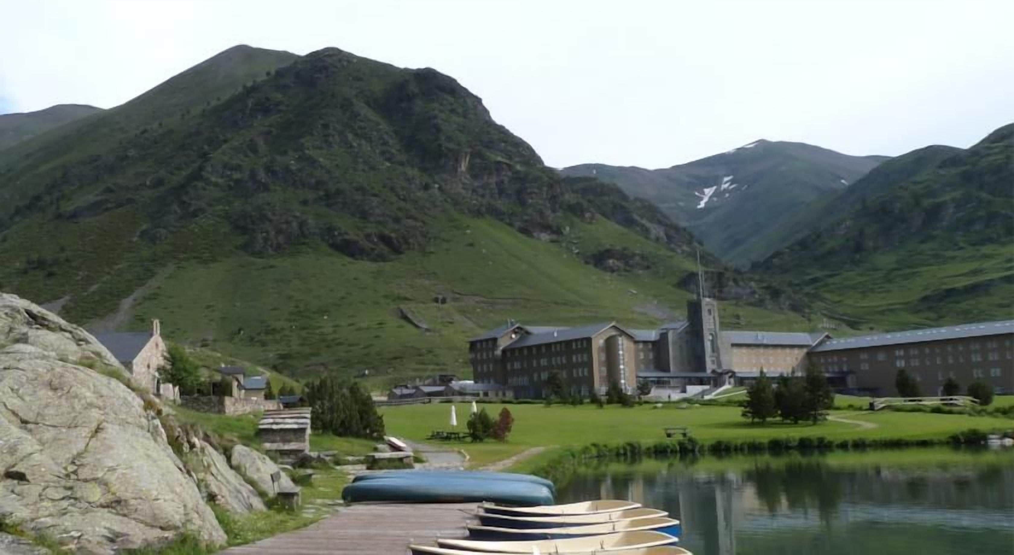 Un paisaje montañoso con un conjunto de edificios y una masa de agua.