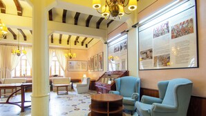 A spacious lobby with a high ceiling, chandeliers, a piano, and a large informational poster. - Vall de Nuria (Queralbs)