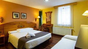 A hotel room with a large bed, a desk, a chair, and a window with curtains. - Vall de Nuria (Queralbs)