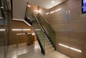 A modern hotel lobby with a wooden wall, a reception desk, and a glass staircase. - Vall de Nuria (Queralbs)