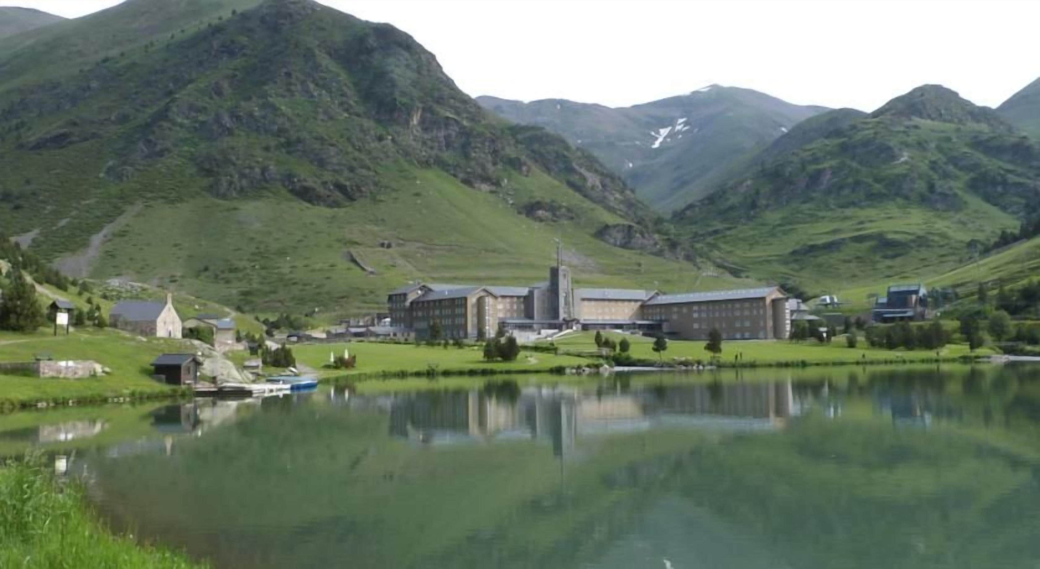 A lakeside view with buildings, a church, and a mountain backdrop.