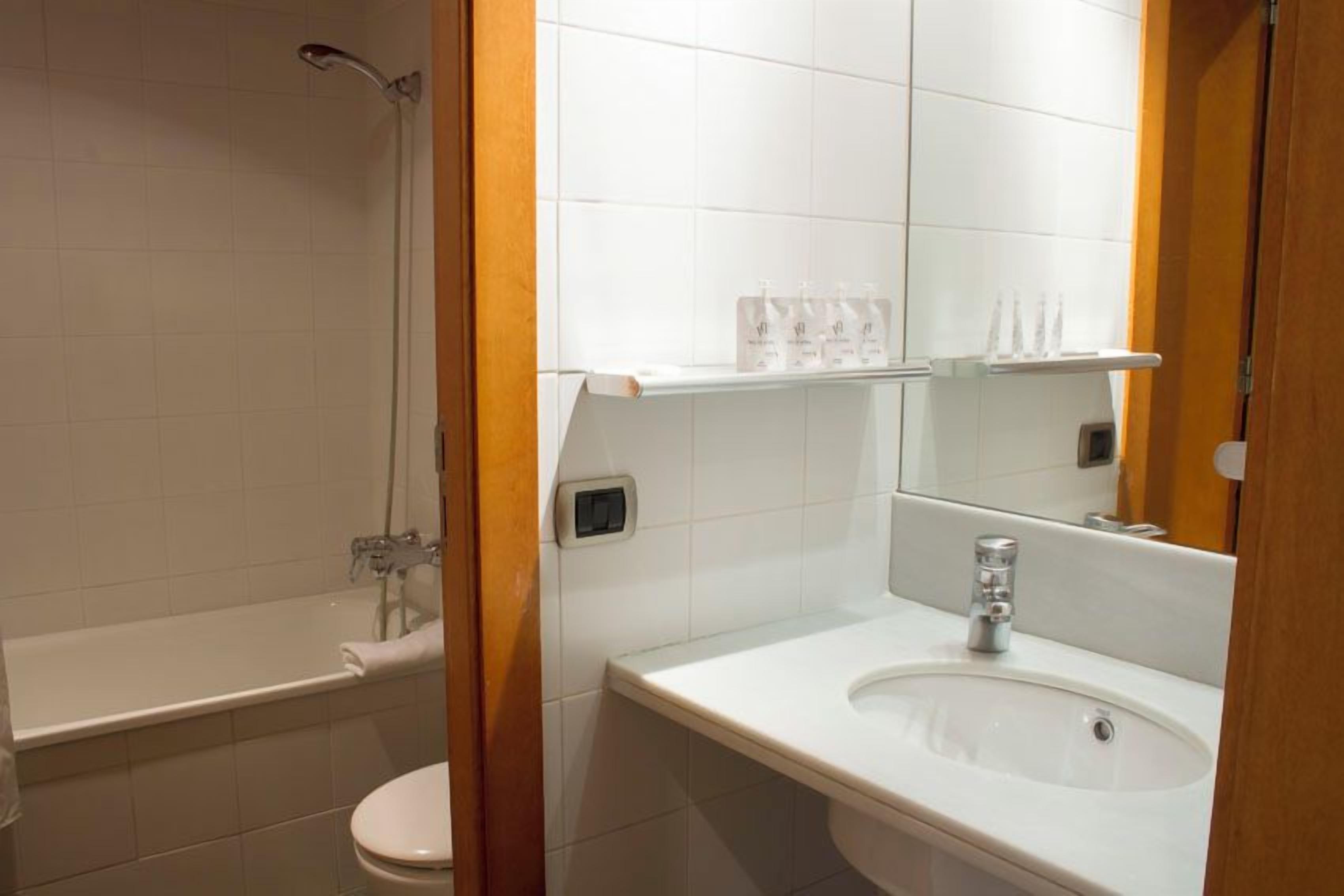 Un baño con bañera, inodoro, lavamanos y espejo.