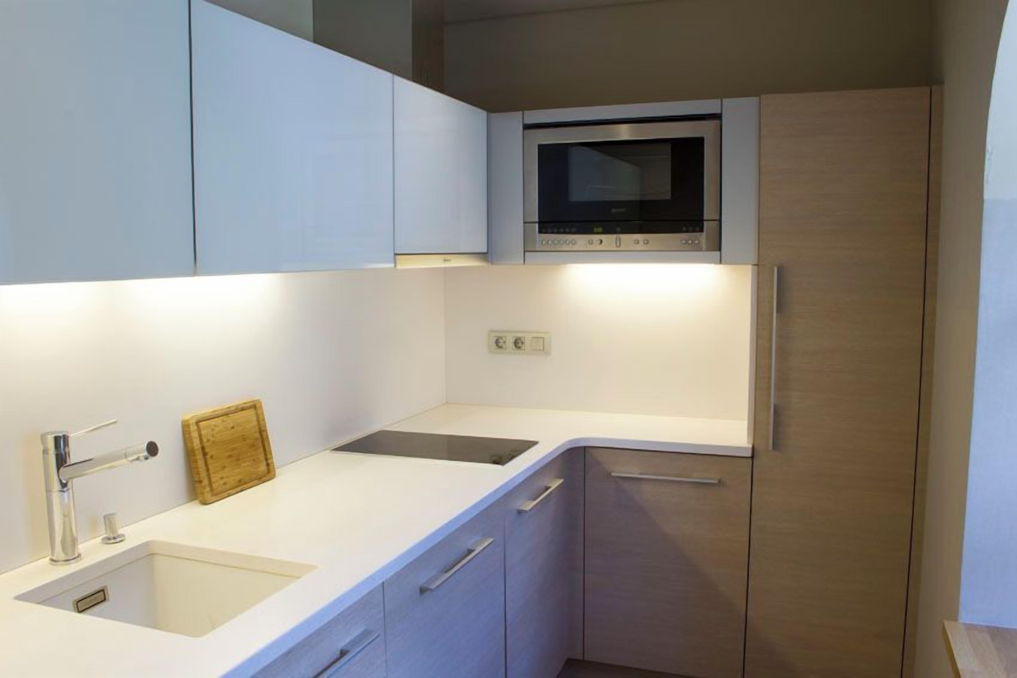 Una cocina moderna con microondas integrado, un lavabo y un armario.
