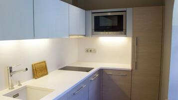 Una cocina moderna con microondas integrado, un lavabo y un armario.
