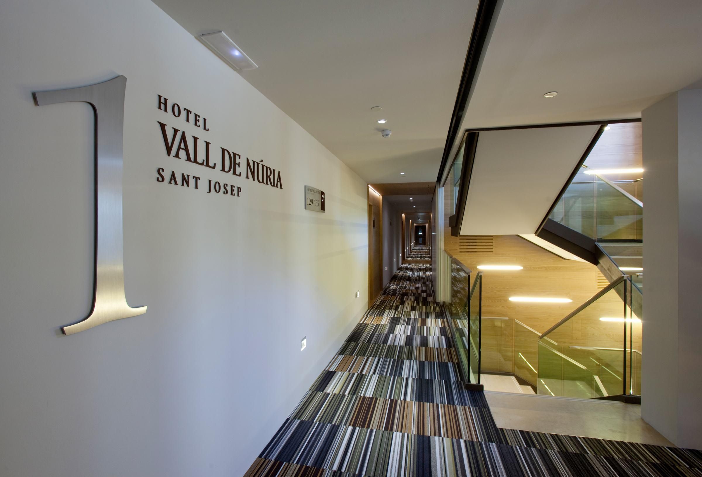 Interior de hotel con diseño moderno, una escalera y una alfombra estampada.