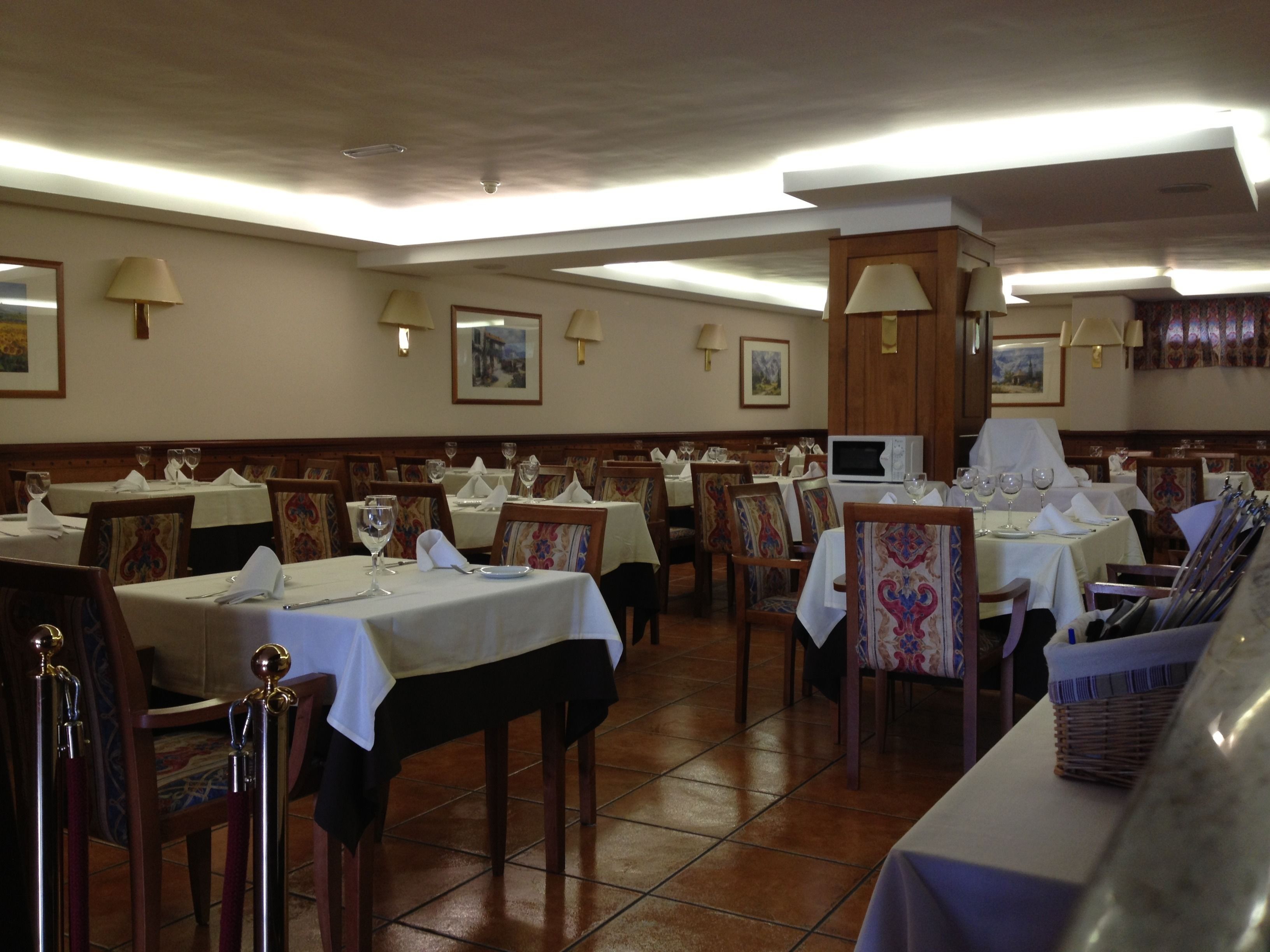 Un restaurante con varias mesas y sillas, cada conjunto con manteles y servilletas blancos.
