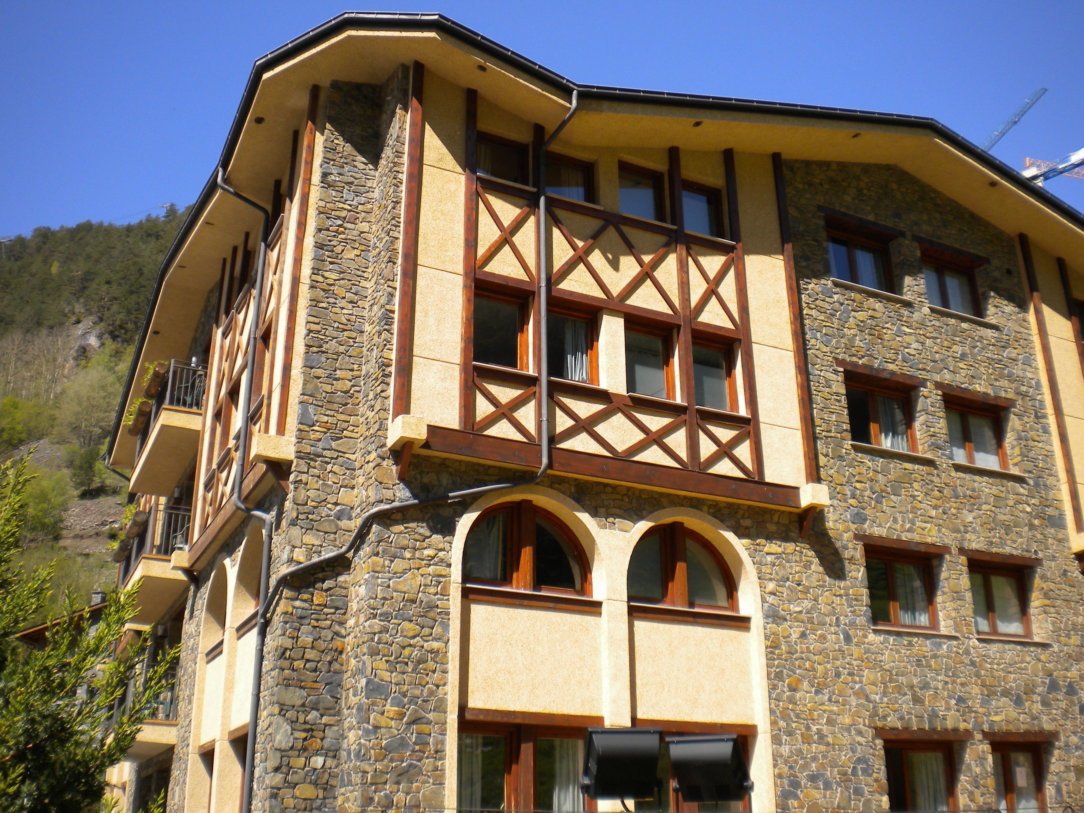 A multi-story building with stone facade, multiple balconies, and large windows.