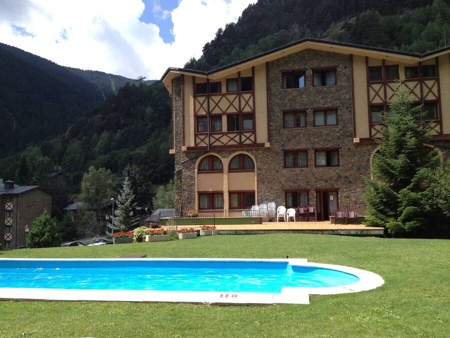 Un hotel con piscina, fachada de piedra y varias ventanas.