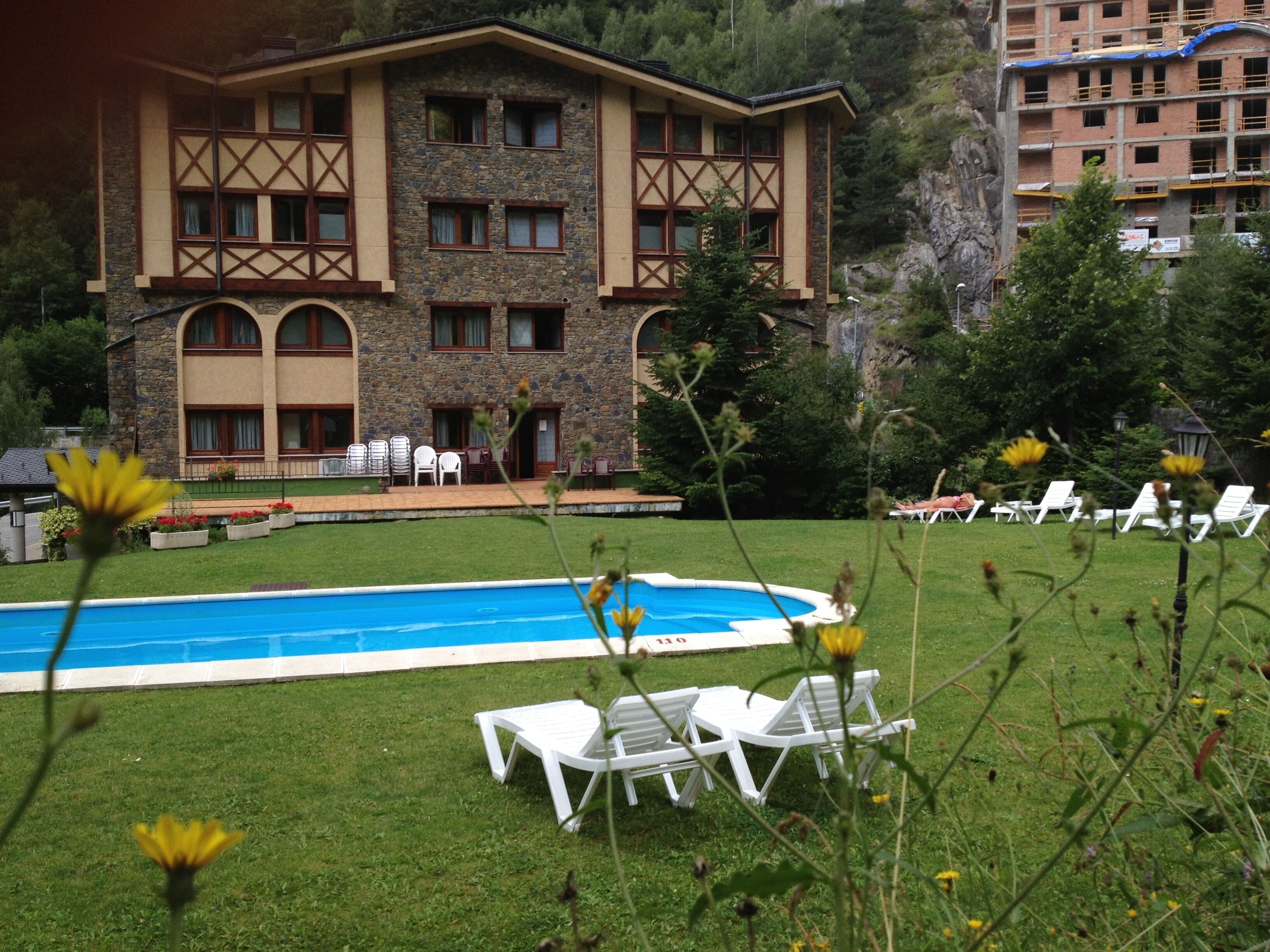 A hotel with a pool, outdoor seating, and a mountainous backdrop.