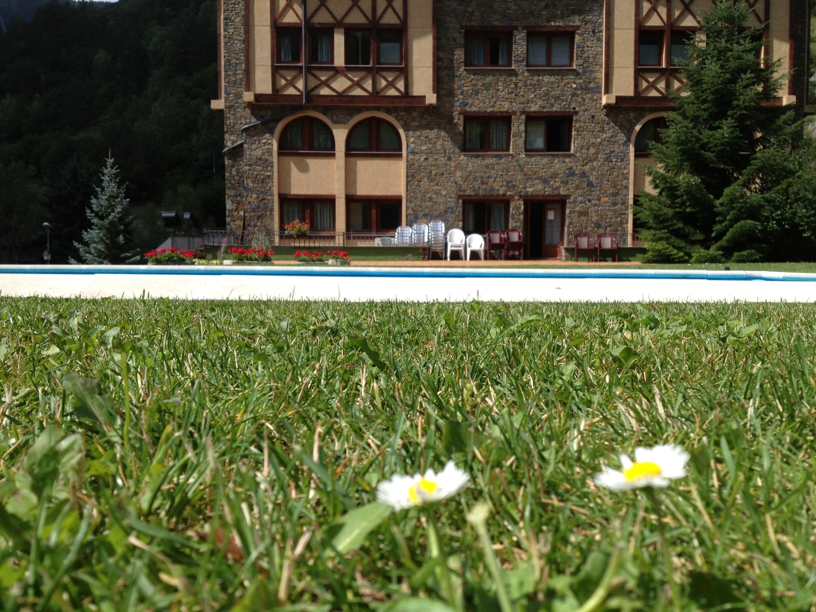 A building with a stone facade, multiple windows, and a pool in the foreground.