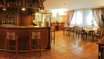 Zona de bar con mostrador, taburetes y gran variedad de botellas. También hay un comedor con mesas y sillas.