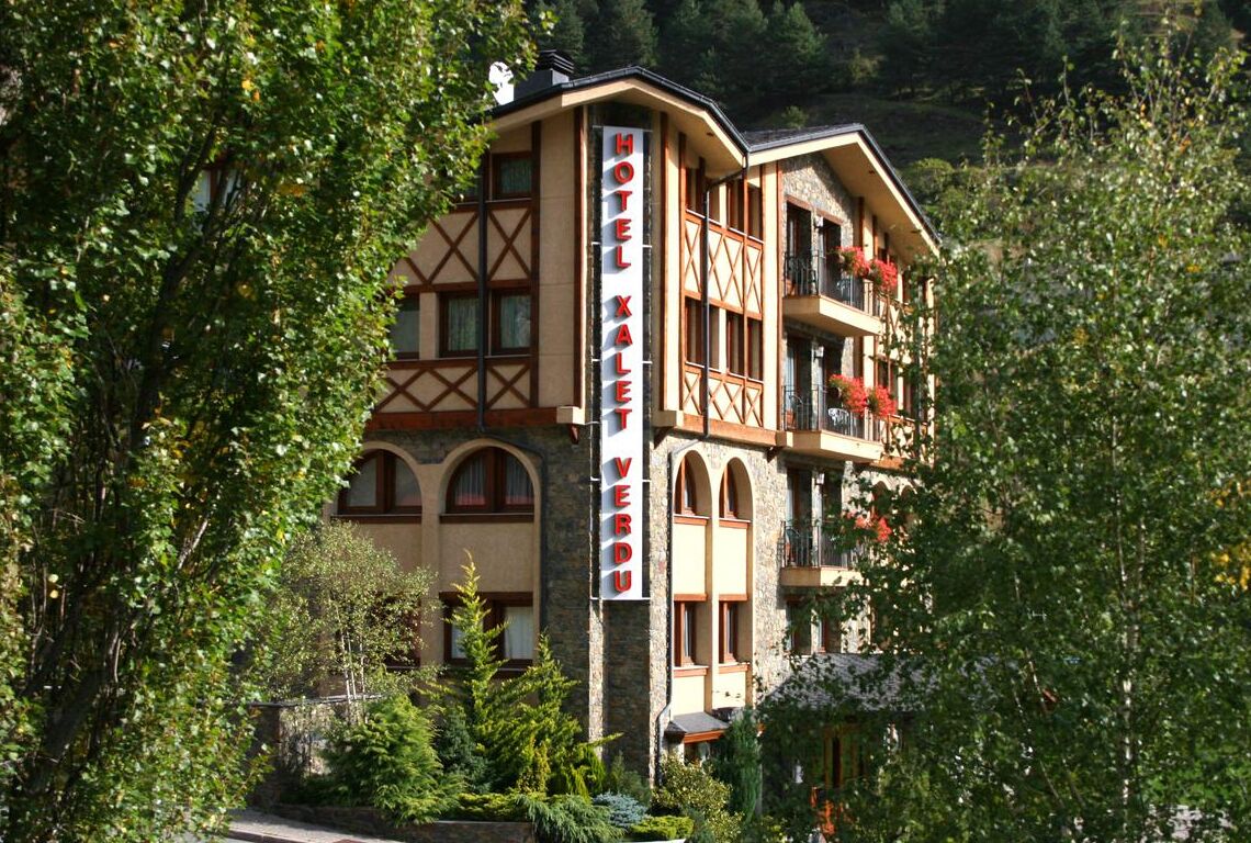 Un hotel de varios pisos con un estilo arquitectónico tradicional, que presenta un letrero llamativo que dice "HOTEL XALET VERDU".