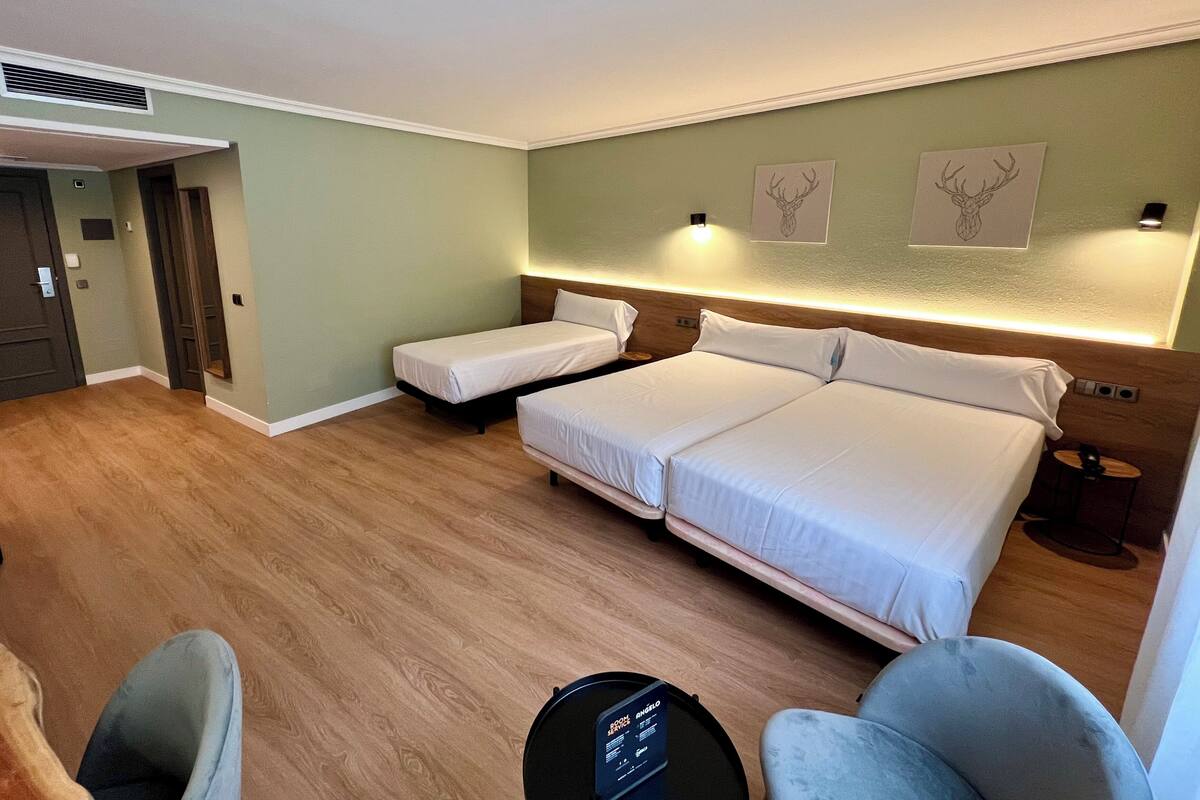 Een hotelkamer met twee eenpersoonsbedden, een bureau, een stoel en een klein tafeltje.