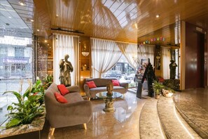 A hotel lobby with a reception desk, a statue, a sofa, and a coffee table.
