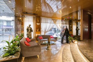 A hotel lobby with a reception desk, a statue, a sofa, and a coffee table.