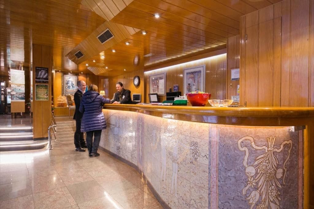 A reception area with a marble counter, wooden paneling, and a clock on the wall.