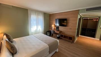 Una habitación de hotel con cama, escritorio, televisor y armario.