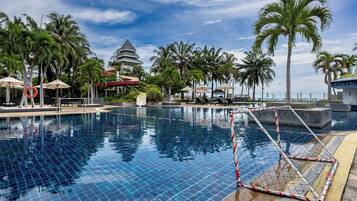 Relax by the rectangular pool surrounded by lush palm trees and a clear sky.