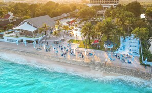 Ein Strandresort mit Poolbereich, Liegestühlen, Sonnenschirmen und einem Beachclub.