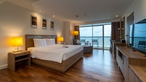 Une chambre d’hôtel moderne dotée d’un grand lit, de lampes de chevet, d’un bureau avec une chaise, d’une télévision et d’un balcon avec vue.