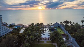Un complexe hôtelier doté d’une piscine, de palmiers et offrant une vue sur le coucher de soleil sur l’océan.