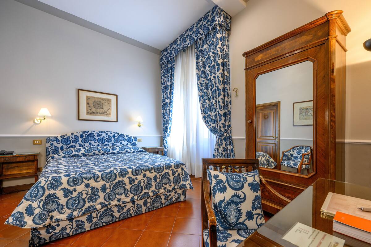 Un dormitorio con una cama, un aparador de madera, una silla y un espejo.