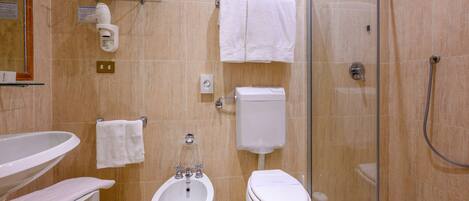 A bathroom with a sink, bidet, toilet, and glass shower enclosure.